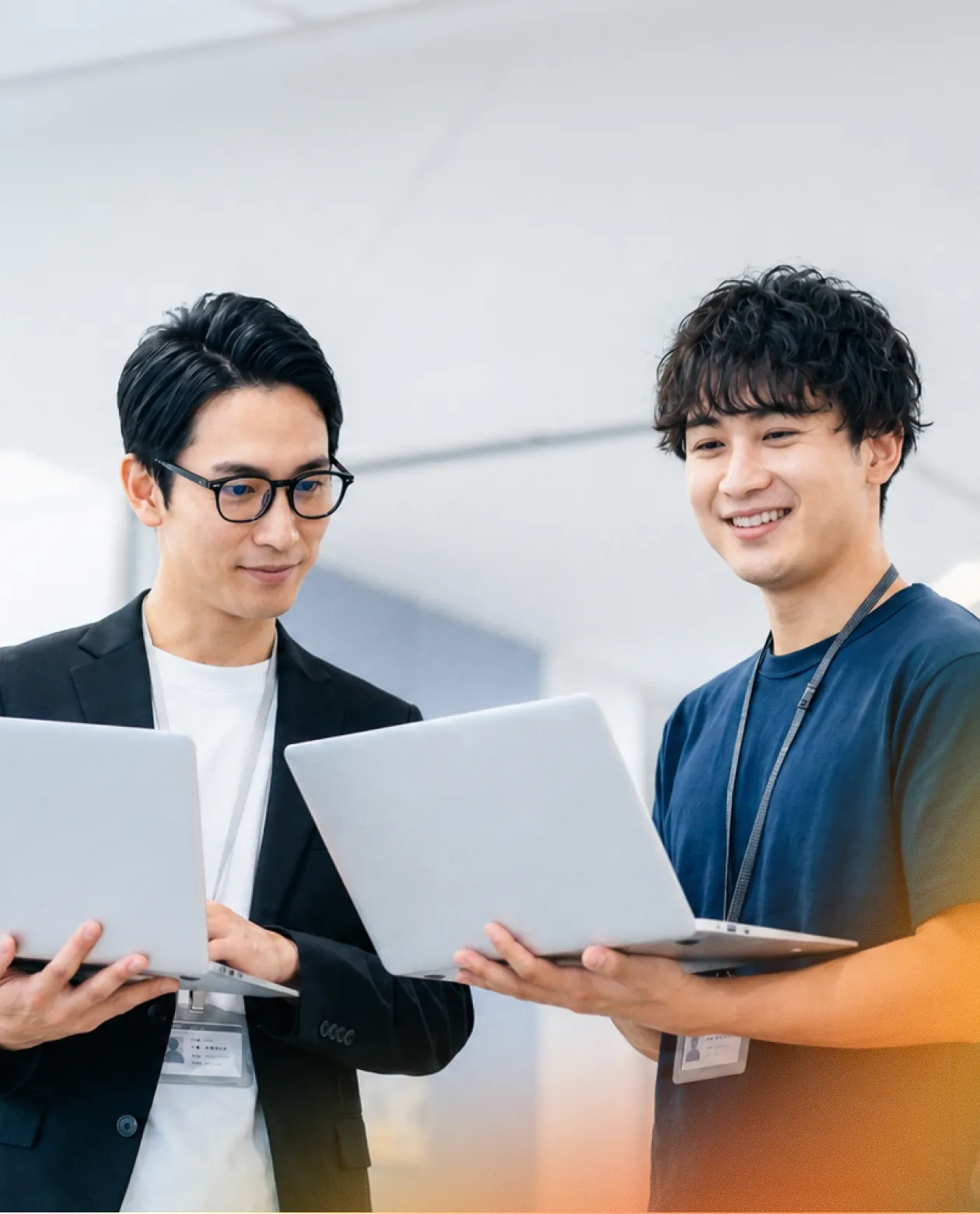 ノートパソコンを持って話す社員2人